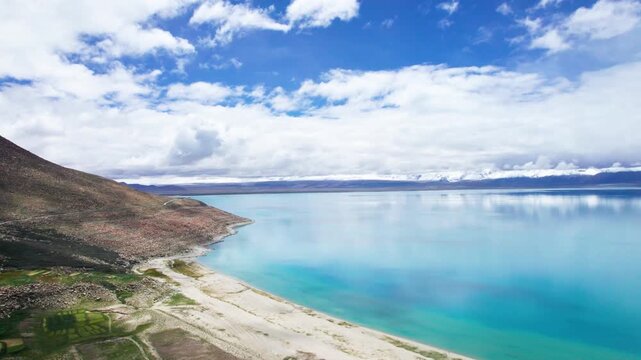 Drone view of Pegu Tso lake or Peikucuo in sunny day in Shigatse, Tibet, China, beautiful peaceful turquoise sea with mountains reflections in Xizang, 4k real time footage travel concept
