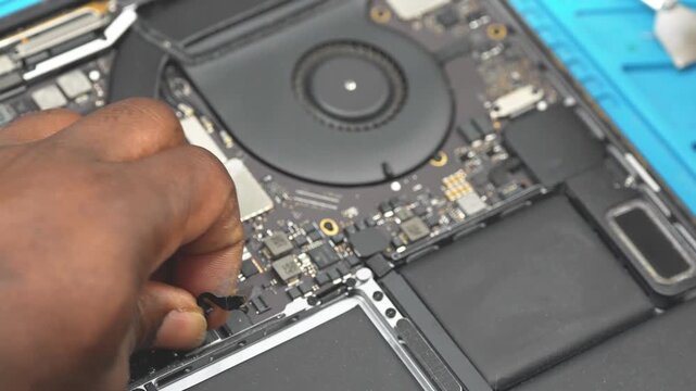 Professional technician soldering components on laptop motherboard in electronics workshop