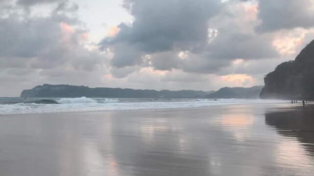 A Calm Beach with Majestic Cliffs, Wet Sand Reflections, and a Cloudy Sky