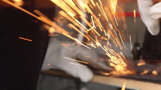 Dynamic golden sparks flying against dark background in industrial metalworking
