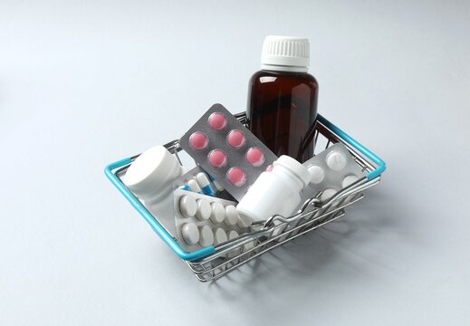 Shopping basket with different medications on grey background