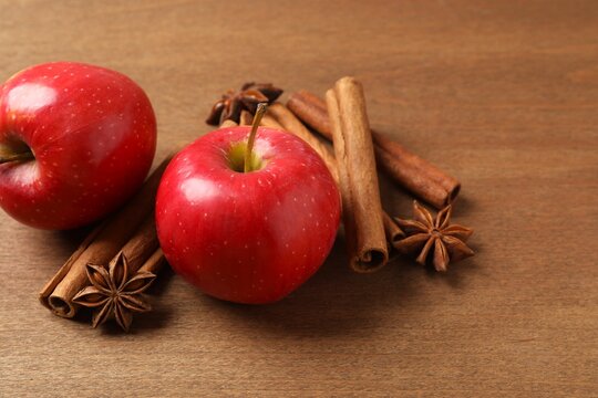 Apples with cinnamon on a textured wooden background. Fragrant red spiced apples with cinnamon sticks and star anise. 