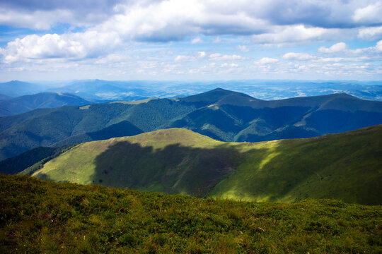 Mountain landscape rolling green ridges beneath dramatic clouds expansive panoramic views.