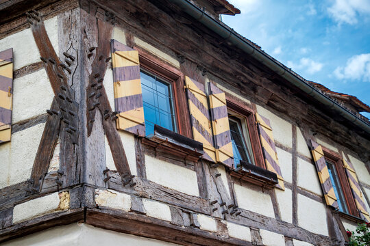 Low angle view of a traditional half-timbered house facade with striped wooden shutters