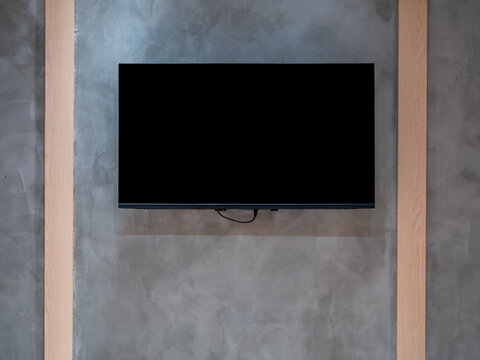Black blank screen smart TV mounted on concrete wall in modern minimalist interior design. Mockup display for digital media, home entertainment, streaming technology and contemporary living space.