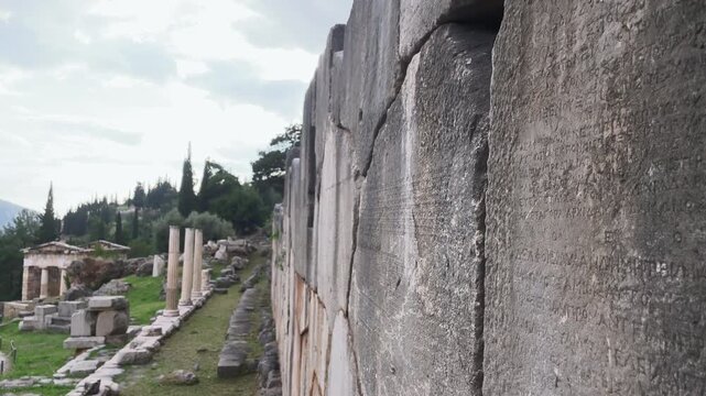 Camera tilts down ancient stone inscriptions at the Sanctuary of Delphi, Greece