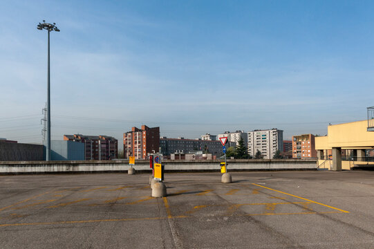 Parcheggio vuoto sul tetto con posti auto delimitati e barriere di cemento. Linee gialle dividono la superficie asfaltata. Un alto lampione si erge sulla sinistra.  Architettura urbana contemporanea.