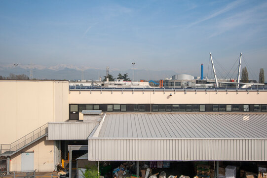 Grande edificio industriale con tetto piano e rivestimento metallico, caratterizzato da ampie vetrate. Sono visibili le attrezzature e le strutture di servizio sul tetto. 