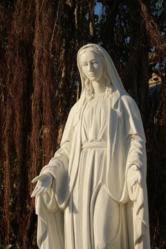 An artistic three-quarter medium view of the stone Ave Maria sculpture emphasizing dramatic light and shadow details.
