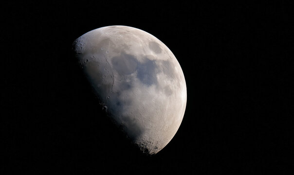A captivating half moon, with its luminous surface, partially obscured by the darkness of space, showcasing lunar craters.