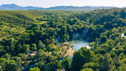Aerial panorama of emerald river and cascading waterfalls surrounded by dense forest © Sanja