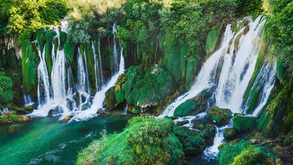 Close view of powerful cascading waterfalls flowing over moss covered rocks © Sanja