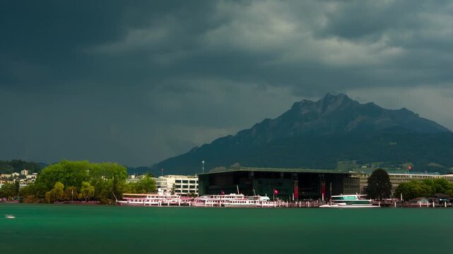 Dramatic stormy time lapse of KKL Luzern and Lake Lucerne in Switzerland with rushing dark clouds over Mount Pilatus