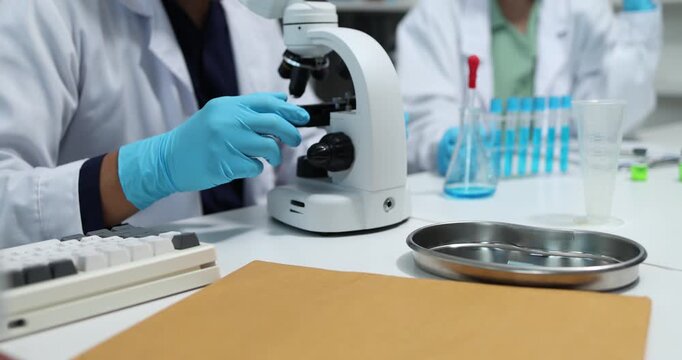 Scientists collaborate in a modern laboratory, analyzing samples with microscopes, pipettes, and test tubes while conducting biomedical research, scientific testing, and laboratory experiments.