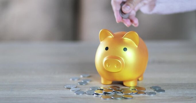 Hand putting a coin into a golden piggy bank, saving money, financial planning, investment, wealth, future savings, budgeting, and financial security, close-up