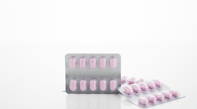Pink tablet pill in pharmaceutical blister pack on white background. Prescription drug medication healthcare and pharmaceutical industry for treatment and clinical use. Pharmaceutical industry.