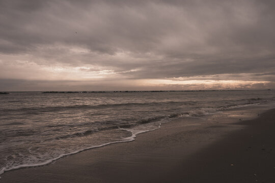 Beach at sunset with a cloudy sky.
Waves crashing on the sandy shore.