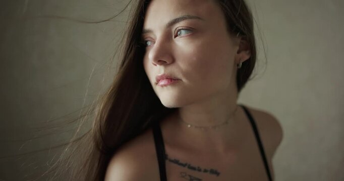 Close up portrait of beautiful thoughtful young woman with hair fluttering in slow motion