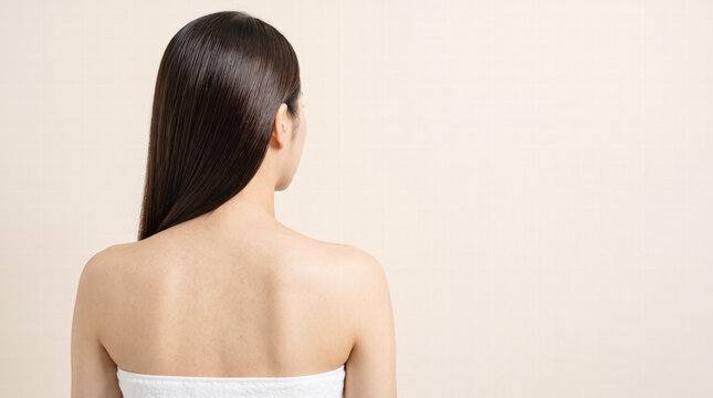 Back view of woman with glossy dark hair, wrapped in towel