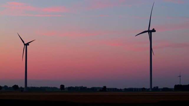 Wind farm, wind turbines, dawn, sunrise, rotating turbine blades, flashing red aviation lights, renewable energy.