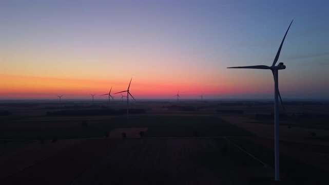 Wind farm, wind turbines, dawn, sunrise, rotating turbine blades, flashing red aviation lights, renewable energy.