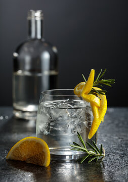 Gin and tonick cocktail in a fogged up glass on a black table.