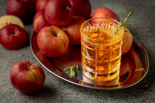 Apple cider and fresh apples on a kitchen table.