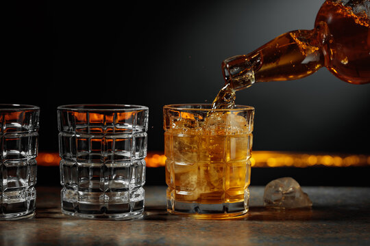 Whiskey is poured into a glass with ice.
