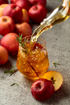 Apple cider is poured from a bottle into a glass.