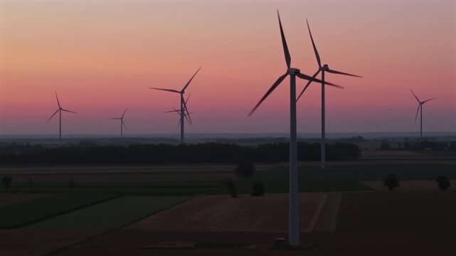 Wind farm, wind turbines, dawn, sunrise, rotating turbine blades, flashing red aviation lights, renewable energy.