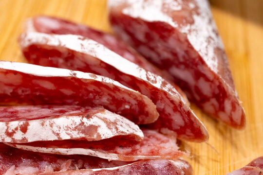 Sliced fuet sausage on wooden board closeup