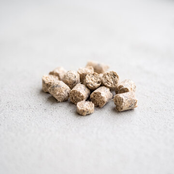 Small pile of compressed organic pellets on a textured gray surface
