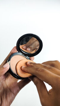 A woman is applying makeup using a powder puff