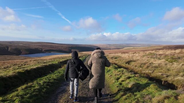 Two figures, people walk side by side along a rural path