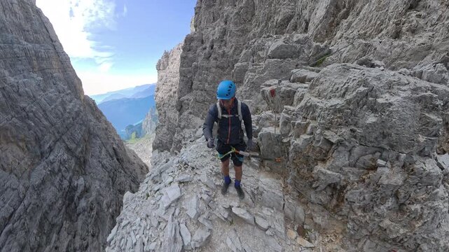 Hiker resting at Bocca Bassa di Massod&igrave; overlooking Lake Molveno on Via Ferrata Bocchette Alte, Brenta Dolomites