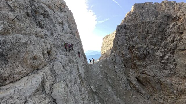 Group of hikers crossing the exposed Bocca Bassa di Massod&igrave; on Via Ferrata Bocchette Alte, Brenta Dolomites