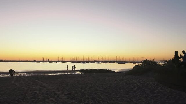 Silhouetted boats at sunset on St Kilda Beach, Melbourne, Australia
