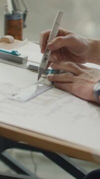 Focused architect working at drafting table with detailed technical blueprints, precision drawing tools, and careful hand-sketching of architectural design plans