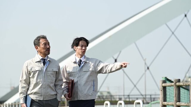 橋梁工事の現場で指差しをしながら打ち合わせを行う30代と50代の作業員