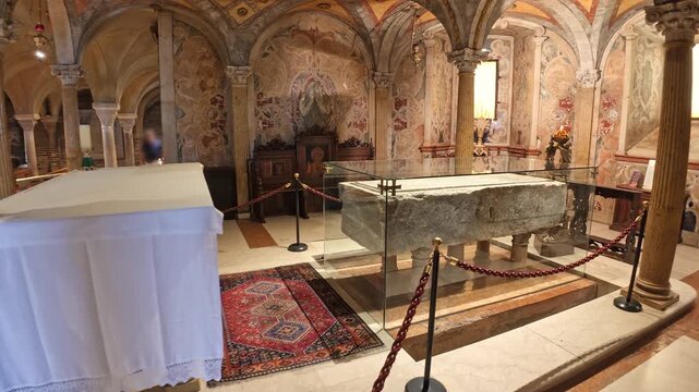 view inside Modena cathedral's crypt, highlighting the ornate stone tomb of San Geminiano amid ancient frescoes and vaulted architecture of Modena city in Italy