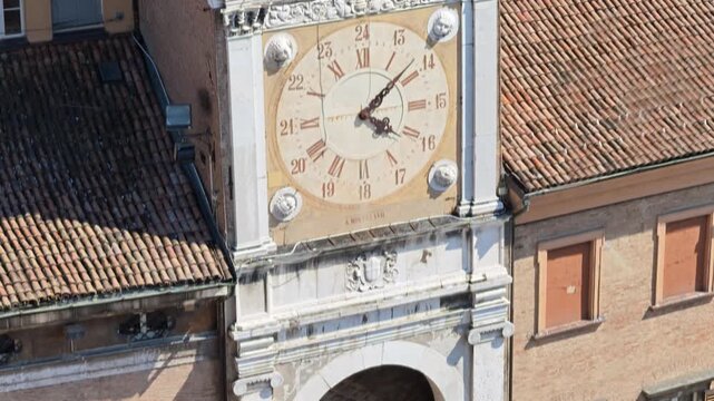 statue of Holy Mary standing gracefully on a crescent moon, positioned within an alcove featuring painted motifs and historic architecture of the clock tower of town hall in Modena, Italy