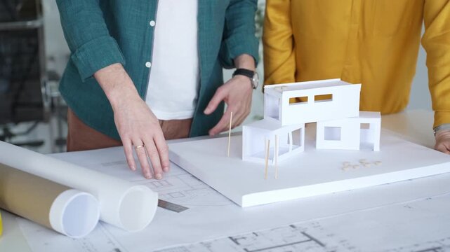 Architects designing residential building structure using scale model and blueprints, planning new construction project. Architecture and business concept