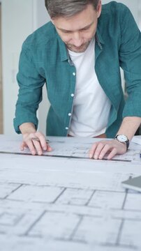 Architect drawing on blueprint plans with ruler and pen, designing new building construction project, engineering workspace. Architecture and business concept