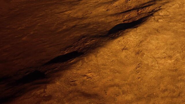The ground is covered with sand under a dim light. Shadows are cast across the surface, creating a contrast between light and dark. The scene shows a simple natural landscape at night.