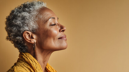 Fototapeta premium beautiful side profile of a senior woman with short silver hair looking up against a warm orange studio background