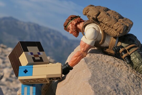 GI JOE action figure of survival instructor Outback, Classified series, pulling Minecraft Steve to on coastal rock in Croatia. Summer clear blue skies. 