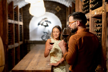 Obraz premium Couple enjoys an intimate wine tasting experience in a cozy cellar