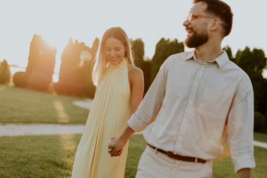 Couple walks hand in hand during sunset at a park in warm light