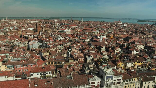 Endless terracotta rooftops and historic brick towers stretch towards the blue Venetian lagoon. A breathtaking urban landscape inspiring luxury travel and idyllic summer European vacations.
