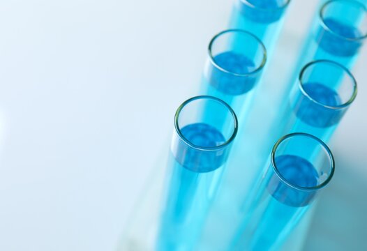 Test tubes with light blue liquid in laboratory, space for text